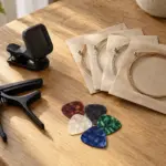 Clip-on tuner, capo, picks and guitar strings on a wooden table